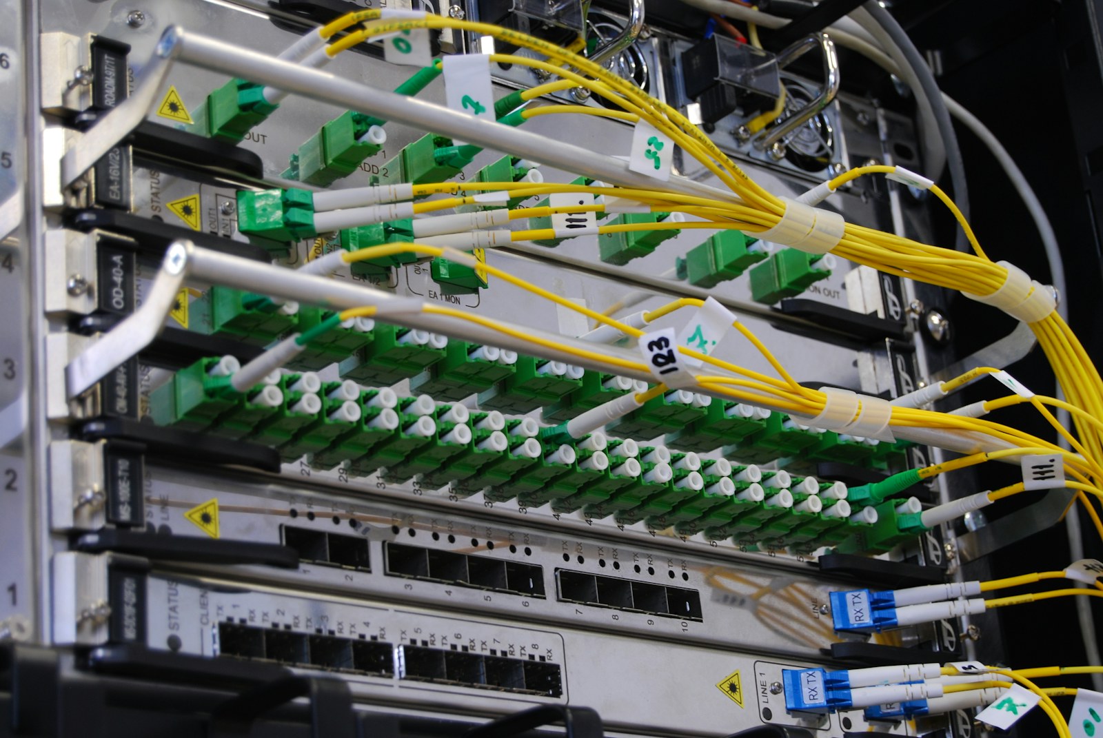 Gula fiberoptiska kablar anslutna i ett telekommunikationsrack.